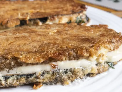 Parmigiana di melanzane ricetta originale: strati dorati e filanti di melanzane fritte, mozzarella e sugo.
