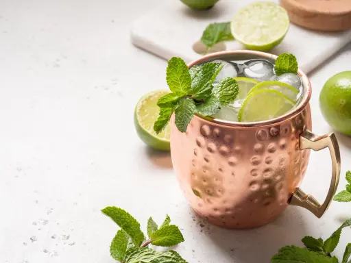 Erfrischender Moscow Mule in Kupferbecher mit Limettenscheiben, Minze und Eis. Perfekt für warme Tage und verschiedene rum sorten.