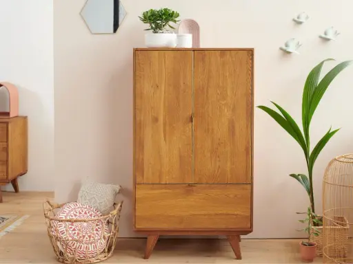 Un buffet haut en bois de chêne, avec un tiroir et deux portes, orné de plantes et d'objets décoratifs.