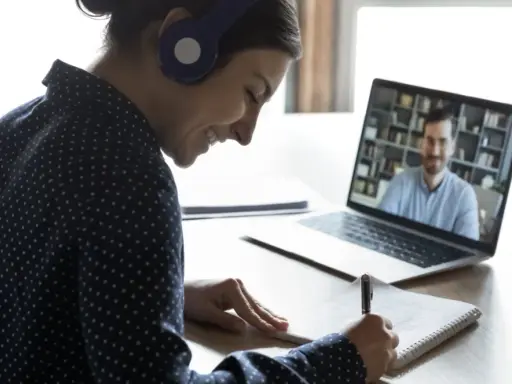 Ragazza con cuffie sorride mentre prende appunti durante una lezione online, comprendendo il vero e-learning significato.
