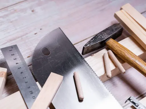 Herramientas para trabajar la madera: sierra, martillo, regla y tacos de madera listos para un proyecto.