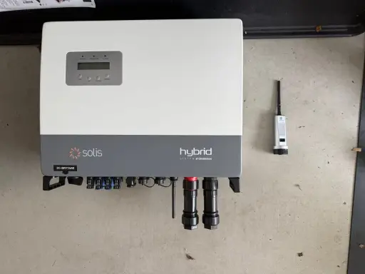 Solis hybrid växelriktare med display och anslutningar. Bredvid syns en liten antenn.