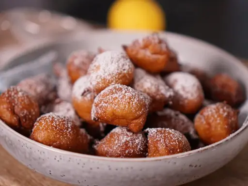 Un bol rempli de beignets dorés, saupoudrés de sucre glace. Parfait pour une recette beignet moelleux rapide.