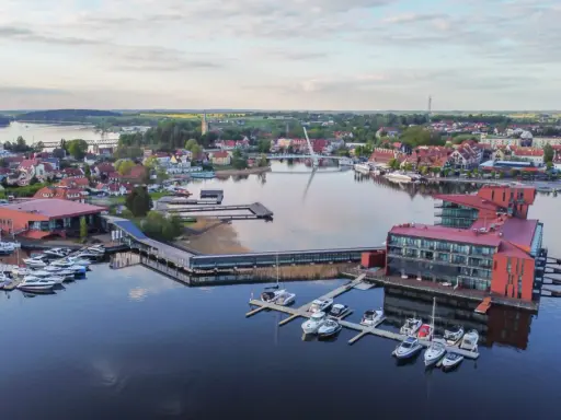 Nowoczesna marina i hotel na Mazurach. Widać tu liczne łodzie, nowoczesną architekturę i malowniczy krajobraz, idealne mazury atrakcje.