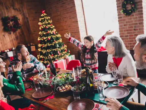 Familia celebrando Navidad en España con niños. Árbol decorado, mesa puesta y regalos. ¡Un plan perfecto donde ir en navidad en españa con niños!