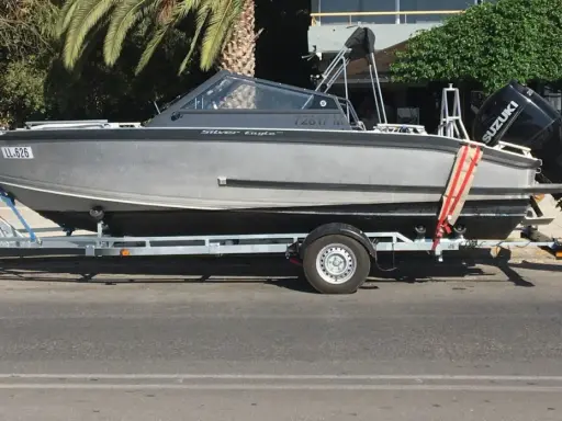 Ein graues Boot, "Silver Eagle", wird auf einem Anhänger transportiert. Der Suzuki Außenbordmotor ist montiert.