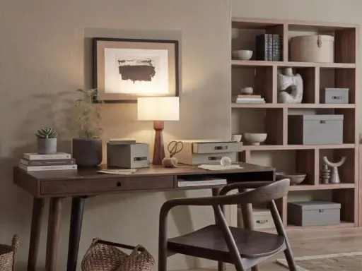 Elegancka organizacja biurka: lampa, rośliny, książki i pudełka do przechowywania tworzą harmonijną przestrzeń do pracy.