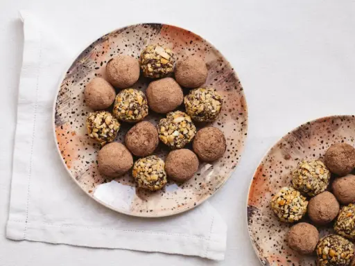 Plato con trufas de chocolate espolvoreadas con cacao y otras cubiertas de frutos secos.