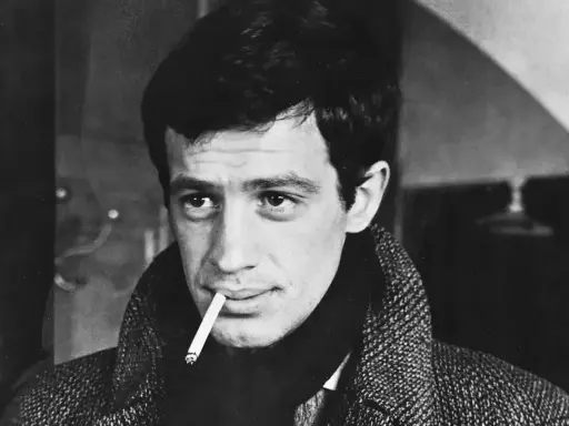 Jean-Paul Belmondo, z papierosem w ustach, w płaszczu, jakby właśnie wysiadł z pociągu do Gdyni.