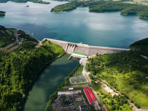 Majestatyczna solina zapora w otoczeniu zielonych wzgórz i błękitnej wody jeziora. Widok z lotu ptaka ukazuje potęgę natury i ludzkiej inżynierii.