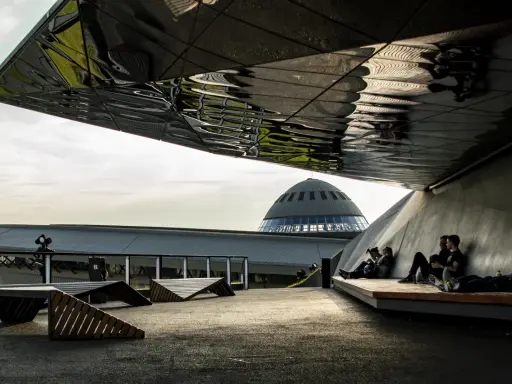Nowoczesna architektura i ludzie odpoczywający pod zadaszeniem. W tle kopuła Muzeum Śląskiego, jedna z głównych katowice atrakcje.