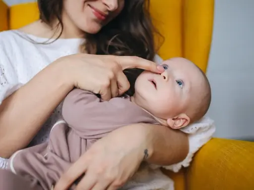 Mama delikatnie dotyka noska dziecka, które ma katar przy ząbkowaniu.