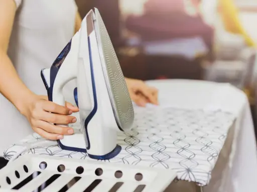 Persona plancha un vestido de satén con cuidado en una tabla de planchar.