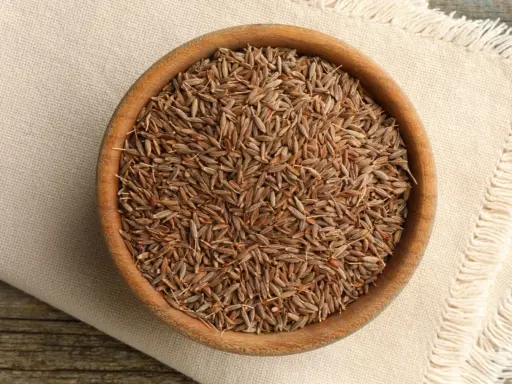 Drewniana miseczka pełna nasion kminu, znanego też jako kumin. Aromatyczna przyprawa gotowa do użycia.