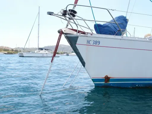 Poids corps mort pour bateau : une ancre est immergée dans l'eau bleue, attachée à un voilier blanc immatriculé HC 389.