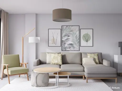 Salón moderno con sofá gris, sillón verde y tres cuadros con motivos botánicos, mostrando diferentes formas de poner cuadros en la pared.