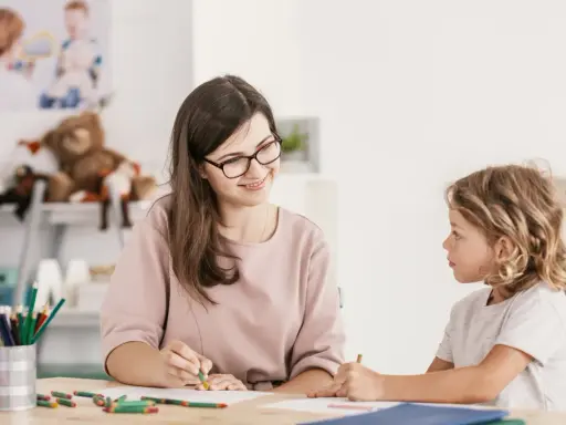 Bambina con ADHD, durante una sessione di diagnosi, disegna con una maestra sorridente.