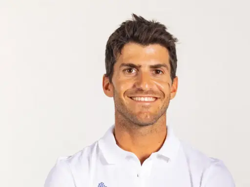 Portrait souriant de Kévin Peponnet, athlète français en polo blanc, sur fond clair.