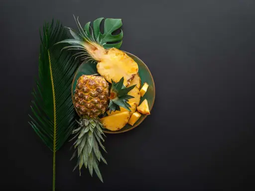 Ananas na talerzu, obok liści. Czy wiesz, że bromelaina co to za enzym?