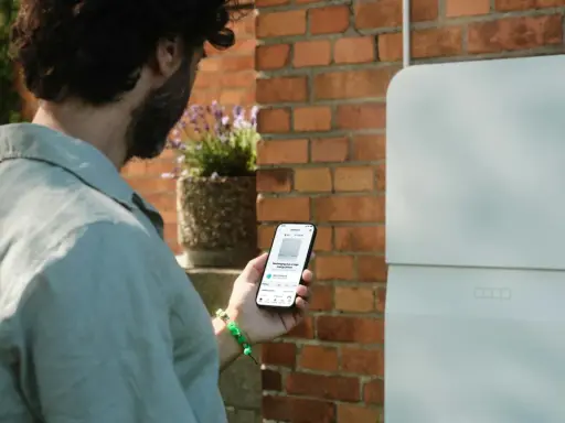 Man kollar sin mobil som visar information om sin batteribank hemma.