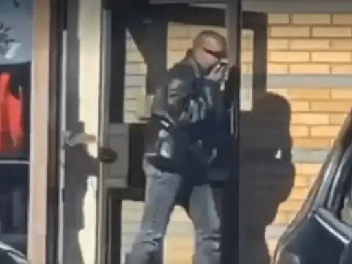 Kanye West i Sverige, klädd i läderjacka och solglasögon, lämnar en byggnad.