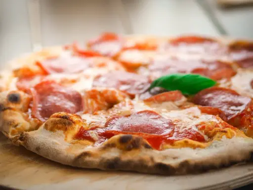 Eine köstliche italienische Pizzateig-Pizza mit Salami und Basilikum, frisch aus dem Ofen.