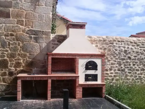 Barbacoa de obra con horno de leña y fregadero, lista para disfrutar de una comida al aire libre.