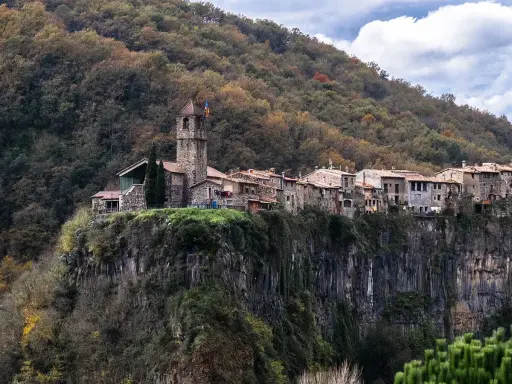 Castellfollit de la Roca, un pueblo medieval colgado sobre un acantilado basáltico, se alza majestuoso entre bosques otoñales.