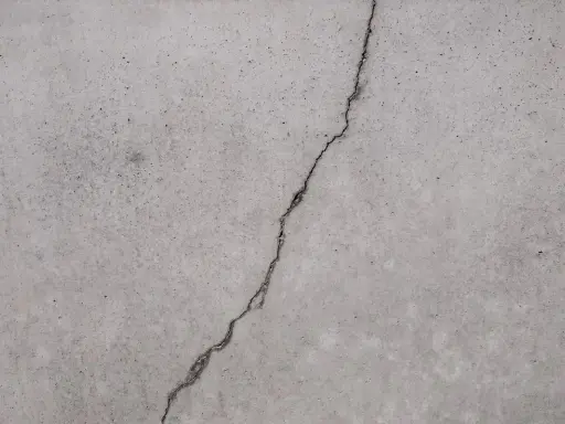 Ein Riss im Betonboden zeigt die Notwendigkeit, den Estrich reparieren zu lassen, um weitere Schäden zu vermeiden.