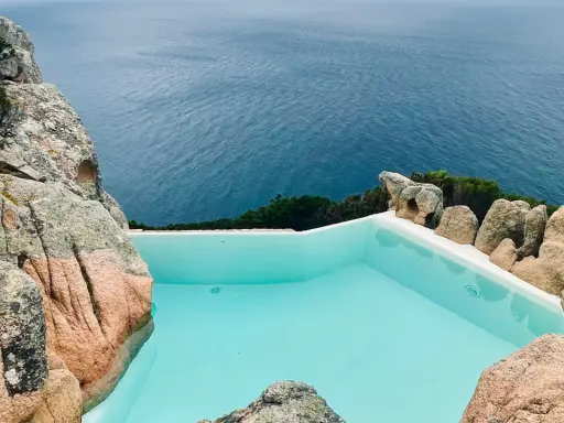 Piscina a sfioro incastonata tra rocce granitiche, con vista sul mare blu intenso. Un angolo di paradiso, forse un progetto di Alberto Ponis.