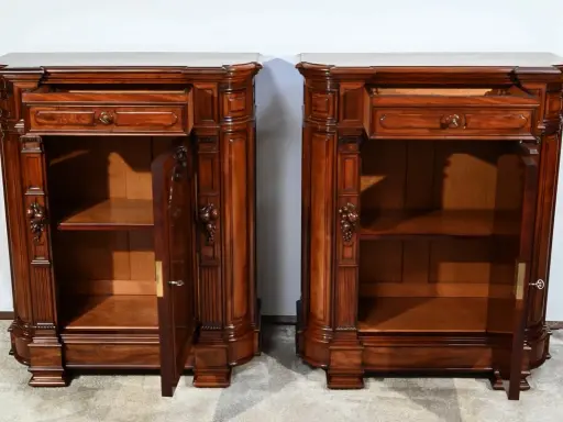 Paire de commodes en bois sombre, style mobilier Napoléon III, avec tiroirs et portes sculptées.