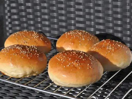 Fünf goldbraune Burgerbrötchen mit Sesam, perfekt für ein Burgerbrötchen-Rezept.