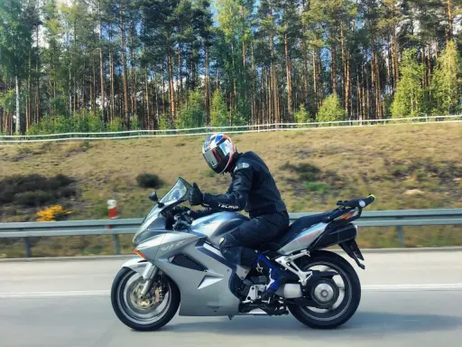 Motocyklista na srebrnej Hondzie VFR 800, mimo że to świetna maszyna, ma swoje wady. Jazda po lesie.