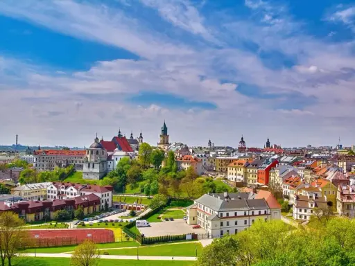 Widok na malownicze miasto w województwie lubelskim. Dachy kamienic, kościoły i zieleń pod błękitnym niebem.