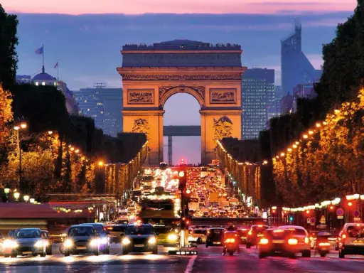 Trafikkaos vid Triumfbågen i Paris. En kvällspromenad här känns som att bada i Paris ljus.