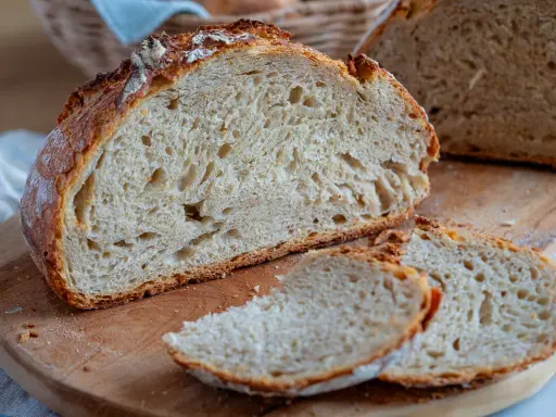 Frisches Brot ohne Sauerteig, mit knuspriger Kruste und luftiger Krume, liegt auf einem Holzbrett.