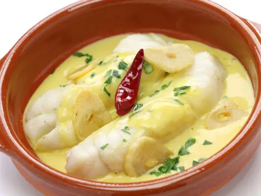 Bacalao al pil pil, uno de los platos típicos vascos, servido en cazuela de barro con ajo y guindilla.