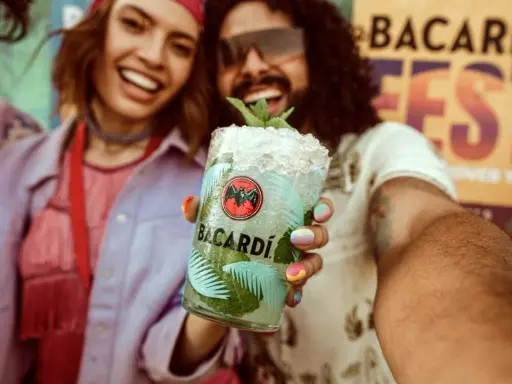 Radosna para świętuje na festiwalu z orzeźwiającym drinkiem Bacardi Mojito.