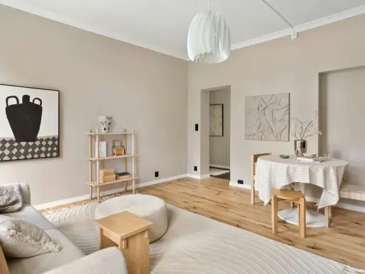 Salón con paredes color crema, ideal para inspirarse sobre de que color pintar la casa. Muebles de madera clara y arte abstracto.