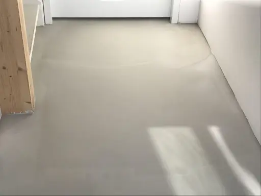 Pavimento in resina grigia, simile a un massetto, con un pilastro di legno. Potrebbe essere un'idea per pavimenti in pvc svantaggi, ma questa è una finitura grezza.