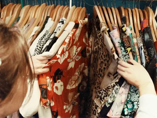 En person letar efter vilken stil har jag bland färgglada kläder med mönster som leopard och blommor.