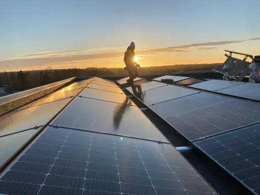 Arbetare installerar solpaneler på ett tak i solnedgången. Gosol Energi AB ser till att framtiden blir grön.