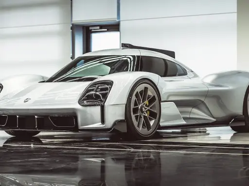 Silberner Porsche Hypercar mit aggressiven Linien und auffälligen Scheinwerfern, bereit für die Rennstrecke.
