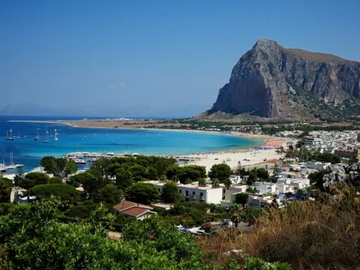 Vista panoramica di San Vito Lo Capo, con la spiaggia affollata e il Monte Monaco. La distanza da Cefalù è di circa 100 km.
