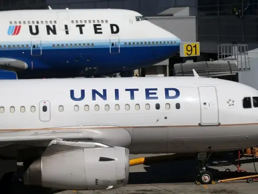 Dwa samoloty United Airlines na płycie lotniska. Jeden z nich to Boeing 747, drugi to mniejszy samolot. W tle widać budynek terminala.