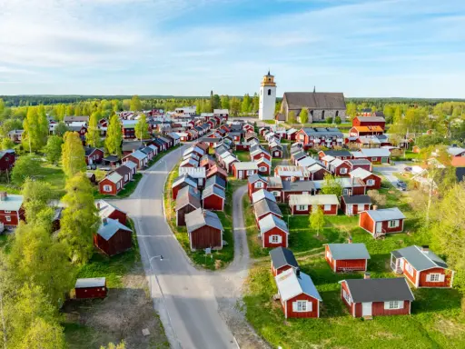Kyrkstaden Luleå, en idyllisk by med röda hus och en kyrka, badar i solljus.