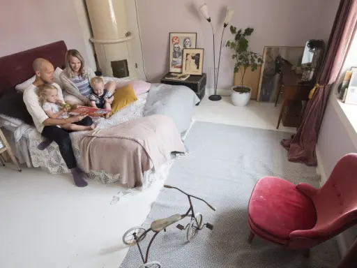 Familjen myser i sängen, pappan läser en bok för barnen. Ett litet bo med barn som njuter av stunden.