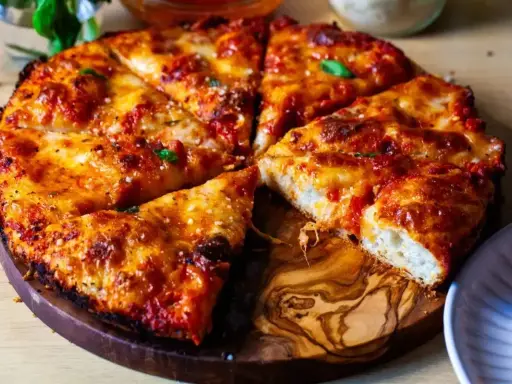Pyszna pizza rzymska z chrupiącym ciastem, ciągnącym serem i aromatycznym sosem pomidorowym, podana na drewnianej desce.