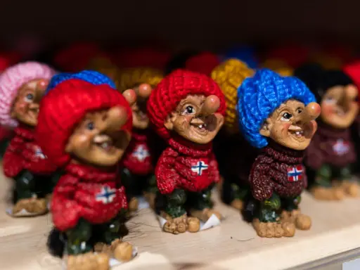 Uśmiechnięte trolle norweskie w kolorowych czapkach i sweterkach z norweską flagą.