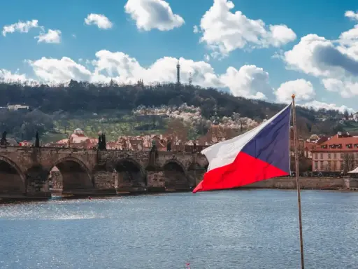 Flaga Czech na tle Mostu Karola w Pradze. Zastanawiasz się, ile idzie paczka z Czech do Polski?